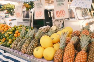 A colorful display of pineapples, melons, and oranges at an outdoor market. Great for travel and lifestyle themes.